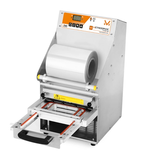 Półautomatyczna zgrzewarka opakowań MCS Tss 102-R z matrycą INFINITY. Stalowa obudowa, duży wałek folii, wyraźny wyświetlacz LED, przesuwany stół do zgrzewania, widoczna przestrzeń na pakowane produkty. Zabezpieczenia w formie oznaczeń ostrzegawczych.