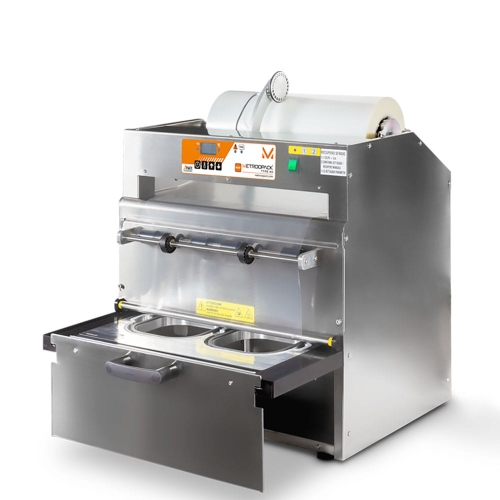 Maszyna pakująca półautomat MCS TSS 112 MAP w kolorze srebrnym, z systemem zgrzewania pojemników. Widoczny panel sterowania z wyświetlaczem, dolna szuflada z dwoma miejscami na pojemniki. Produkt stoi na tle białym.