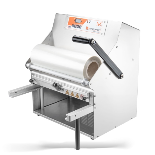 Zgrzewarka ręczna METROOPACK TSM-105 do pojemników, z białą rolką folii, metalowa obudowa, panel sterujący z wyświetlaczem. Produkt stoi na podłodze, z widocznymi uchwytami i elementami regulacyjnymi.