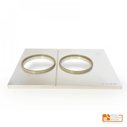 Matryca MCS do zgrzewarek METROOPACK z dwoma okrągłymi wytłoczeniami, wykonana z metalu. Ułożona poziomo, z widocznymi obręczami. Przeznaczona do zgrzewania kubków jogurtu lub deserów. Prosta, jasna powierzchnia. Logo METRO CATERING SYSTEM w dolnym rogu.